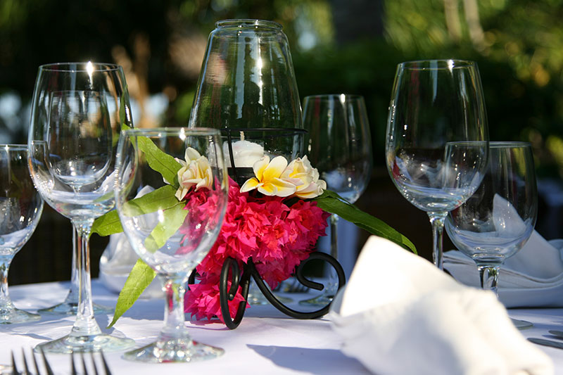 Wedding table laid with wine glasses and a frangipani and bougainvillea centrepiece in the garden at Santai Hotel Amed in east Bali