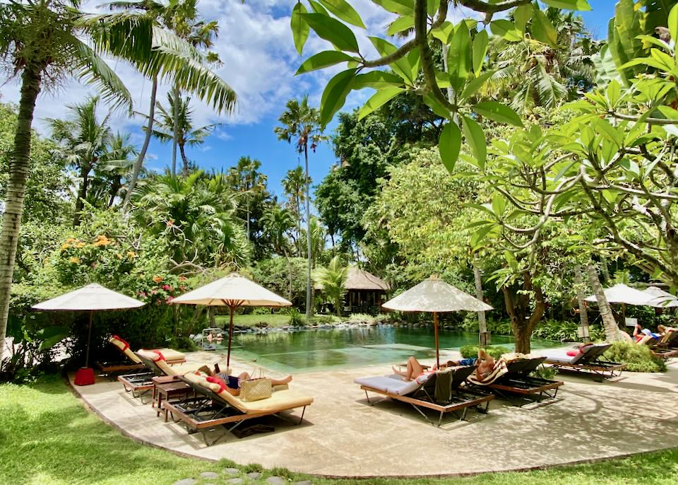 Pool and sun loungers among the tropical gardens at Segara Village Hotel, Sanur