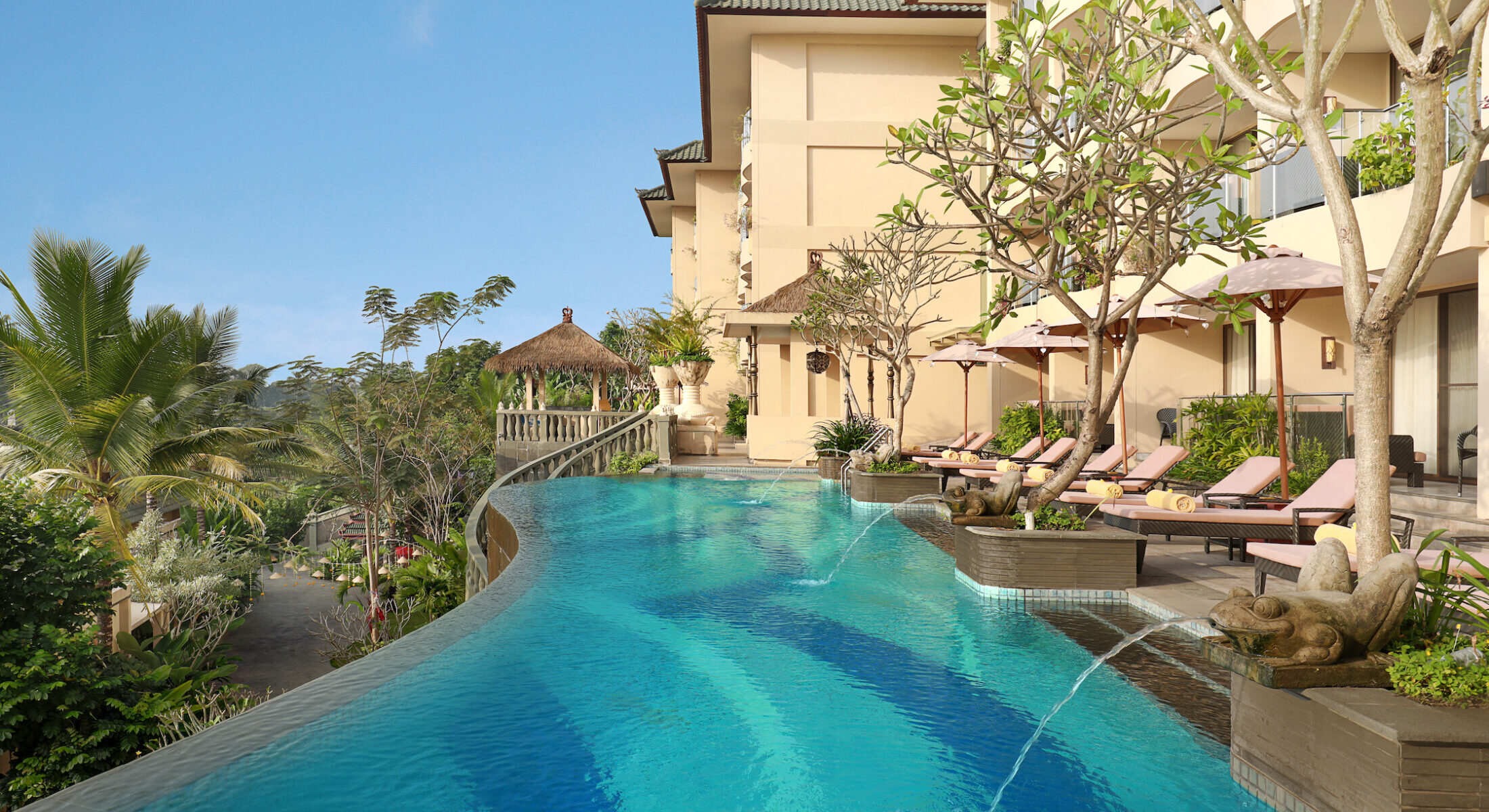 Infinity pool with loungers and resort building with valley views at SereS Springs Resort Ubud