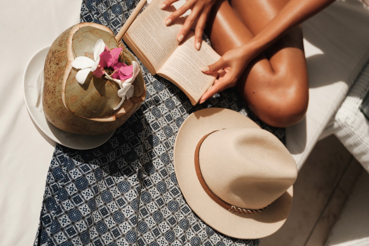 Guest reading on a day bed with a coconut and a hat at Seri Resort Gili Meno
