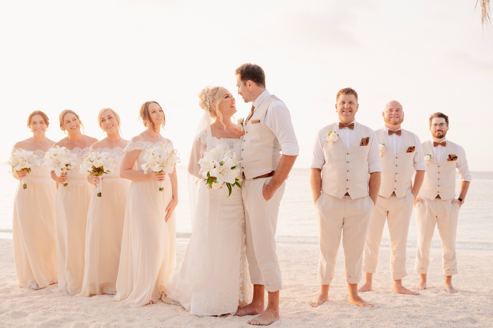Bride and groom with their bridesmaids and groomsmen in cream and linen on the sand at sunset at Seri Resort Gili Meno, off Lombok