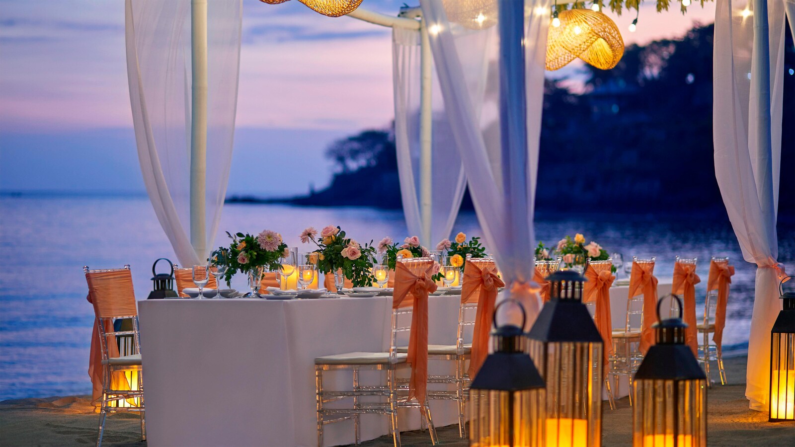 Long table with peach chair sashes and candles set on the sand at twilight, Sheraton Senggigi Beach Resort, Lombok