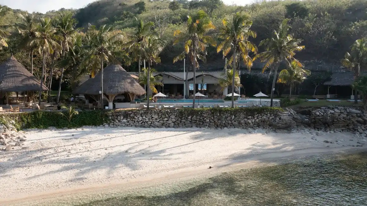 Silo Beach Club seen from the water, thatched pavilions above a white-sand beach on Nusa Penida, Bali