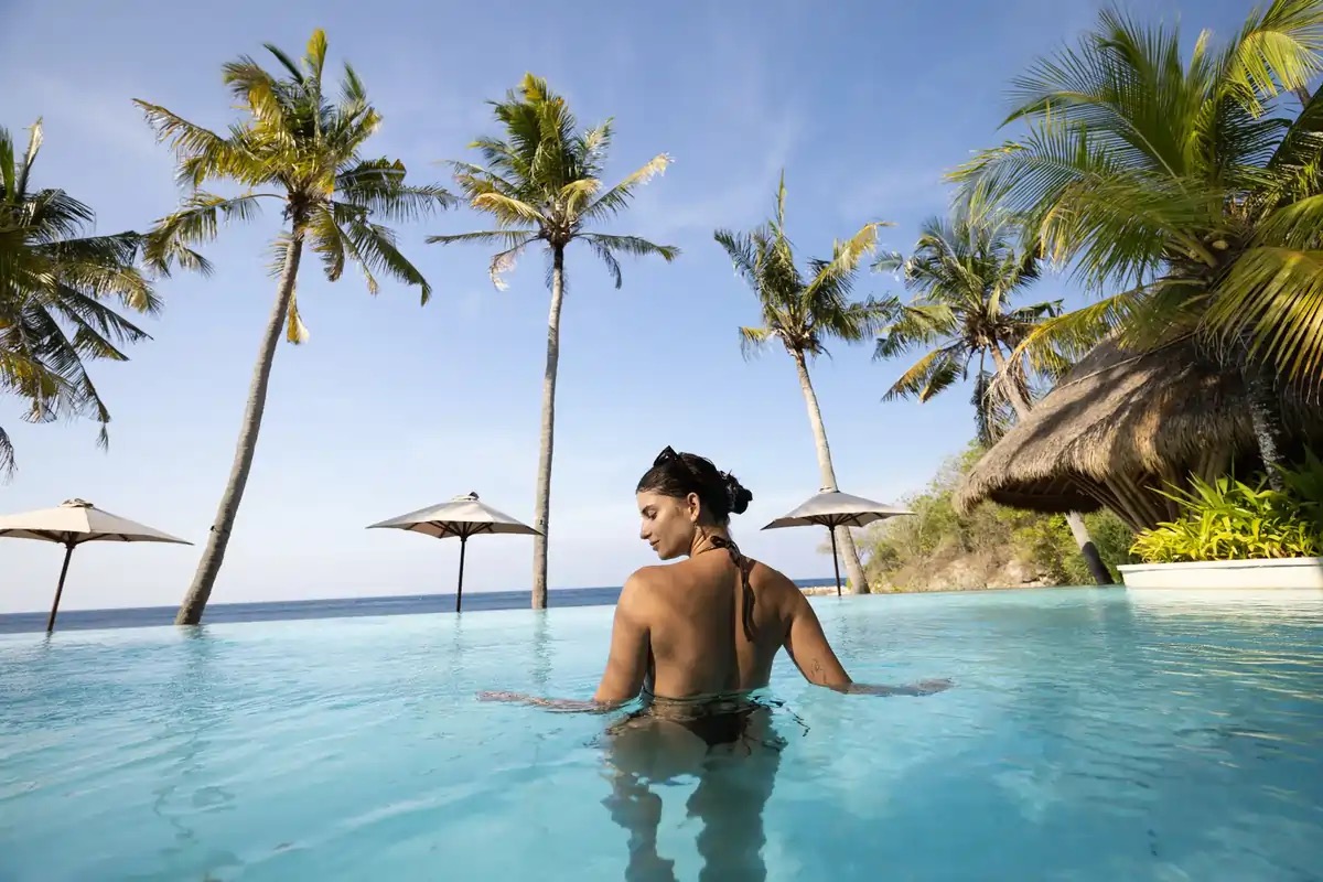 Ocean-facing infinity pool framed by coconut palms at Silo Beach Club, Nusa Penida, Bali