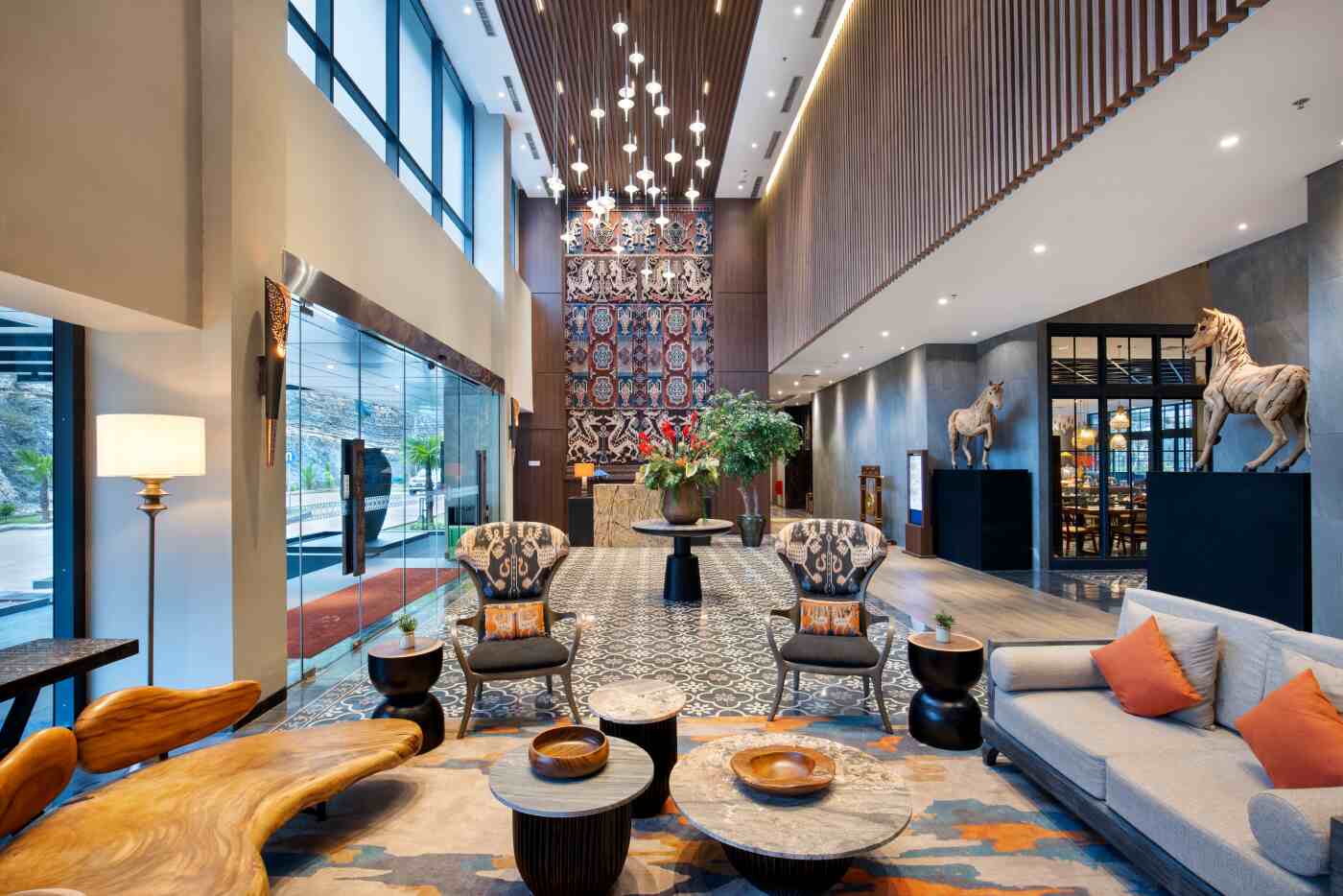 Double-height lobby with Sumbanese textiles and carved horse figures at Sima Hotel Sumba, Sumba