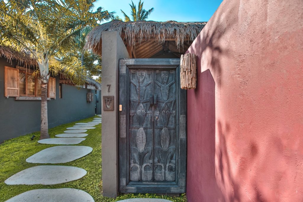 Carved timber door and stepping-stone path to a villa entrance at Slow Private Pool Villas, Gili Air