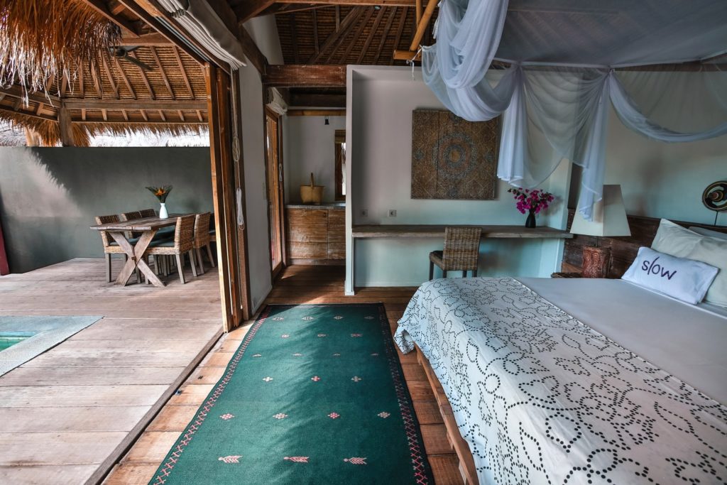 Villa bedroom with a gauze canopy and a terrace dining table at Slow Private Pool Villas, Gili Air