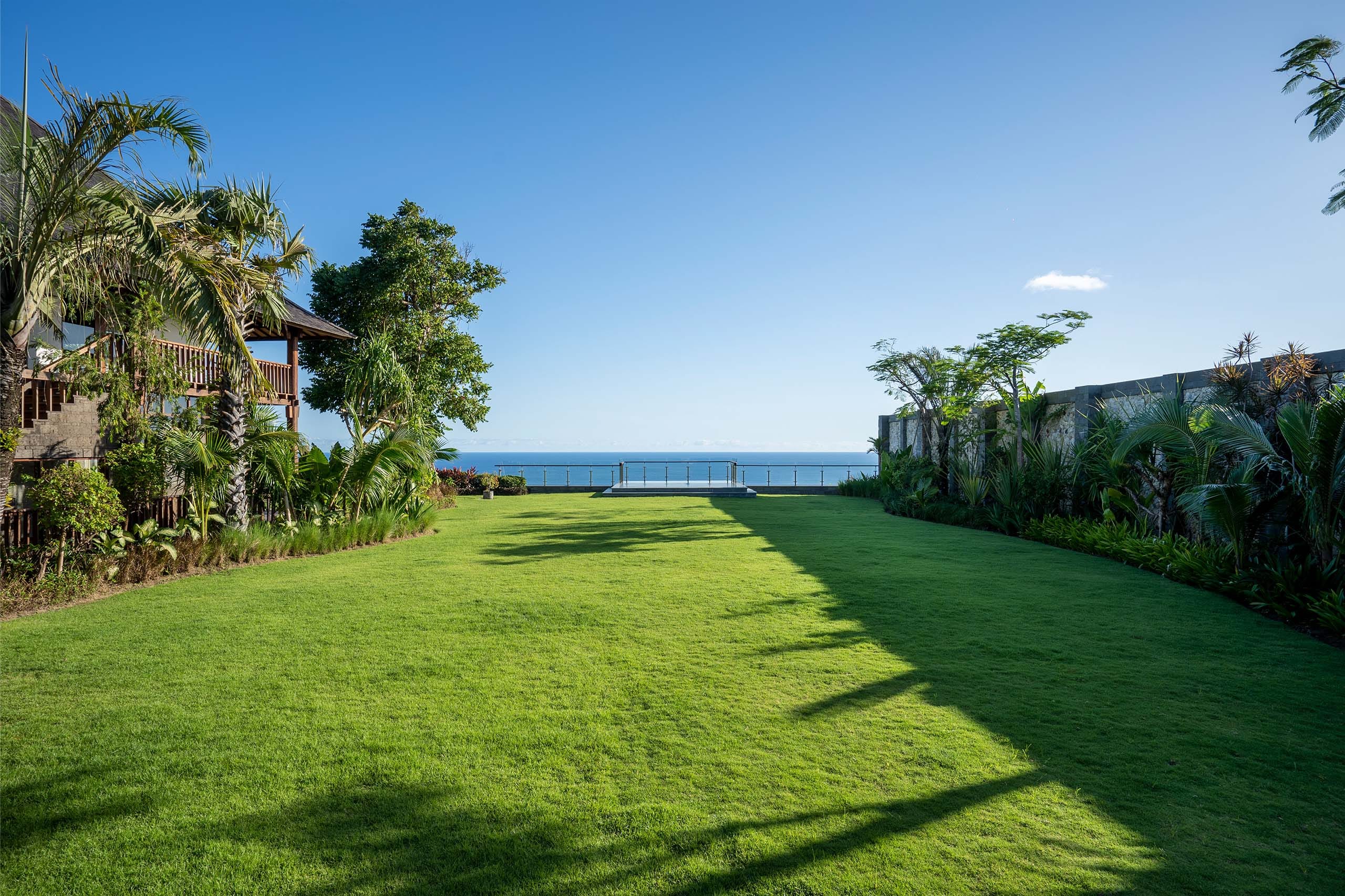 Ocean-edge lawn and pool at Stone Villas Uluwatu on the cliffs of Pecatu