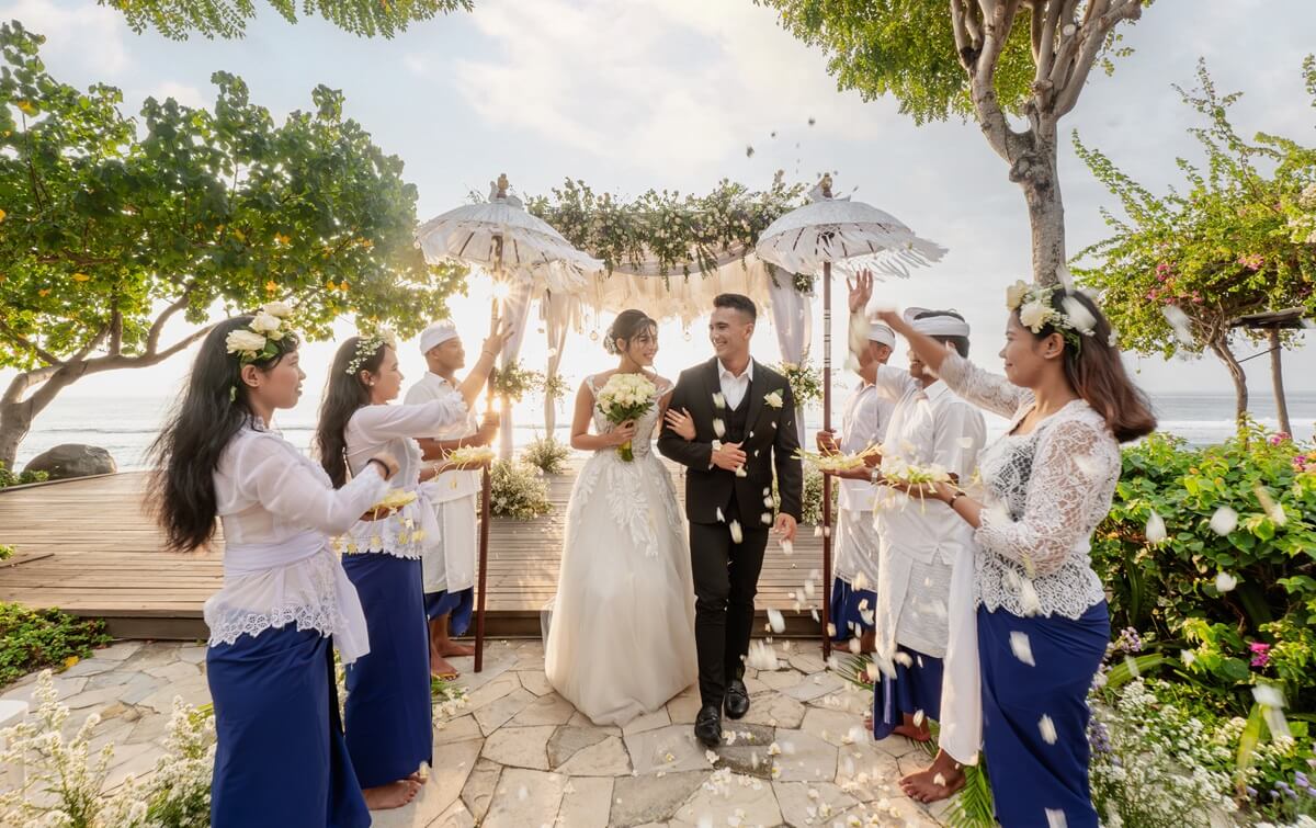 Newlyweds showered with petals under traditional parasols beside the beach at Sudamala Resort, Senggigi, Lombok