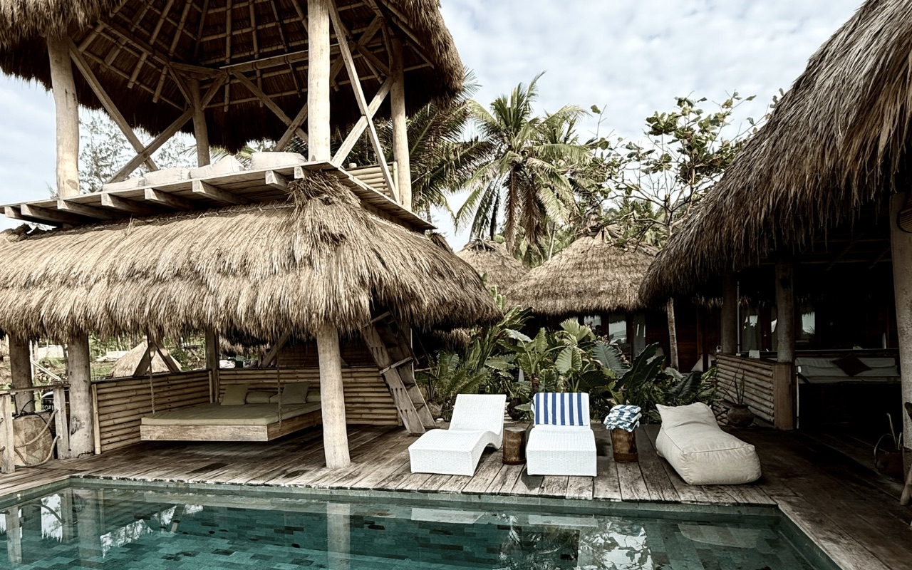 Swimming pool and sun loungers under the thatched pavilions at Sumba Beach House, Sumba