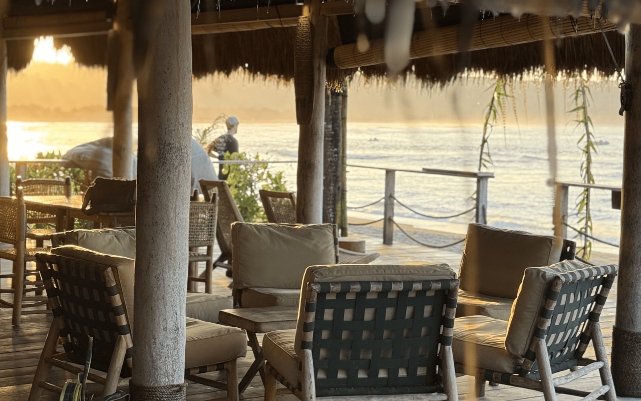 Lounge seating under the thatched beach pavilion facing the sea at golden hour at Sumba Beach House, Sumba