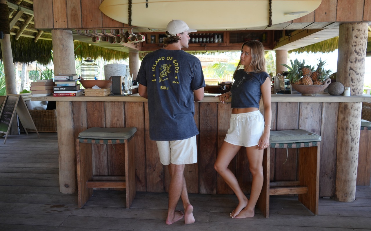 Two guests at the timber bar counter under stored surfboards at Sumba Beach House, Sumba