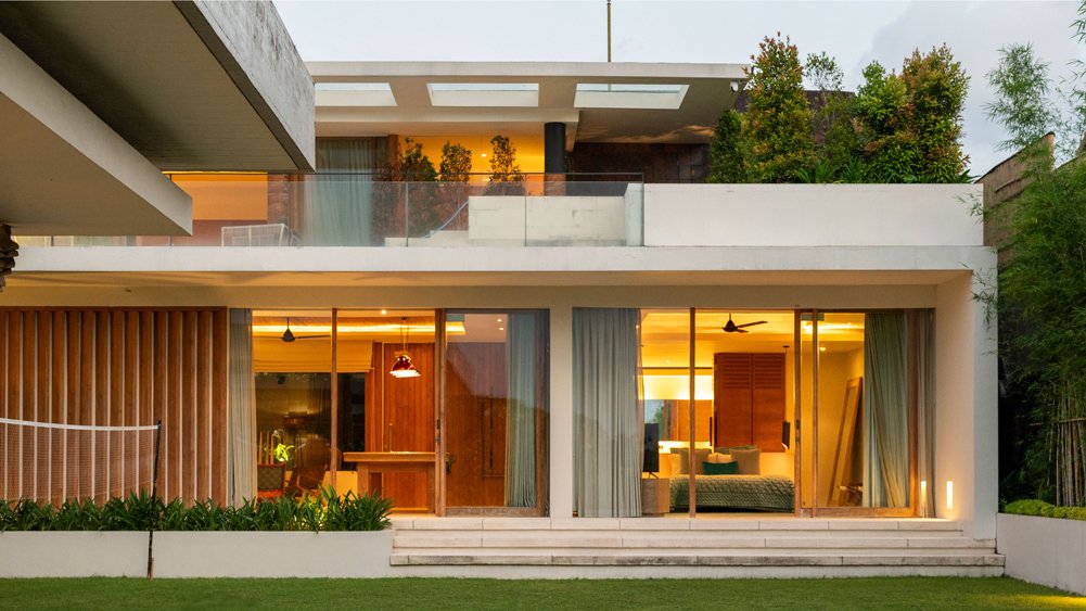 The Iman Villa illuminated at night with pool glowing, creating an enchanting evening ambience