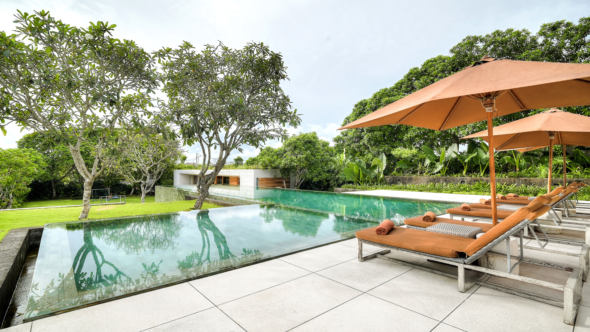 The Iman Villa's infinity pool and open living pavilion with terraced rice-field gardens beyond, in Pererenan, Canggu