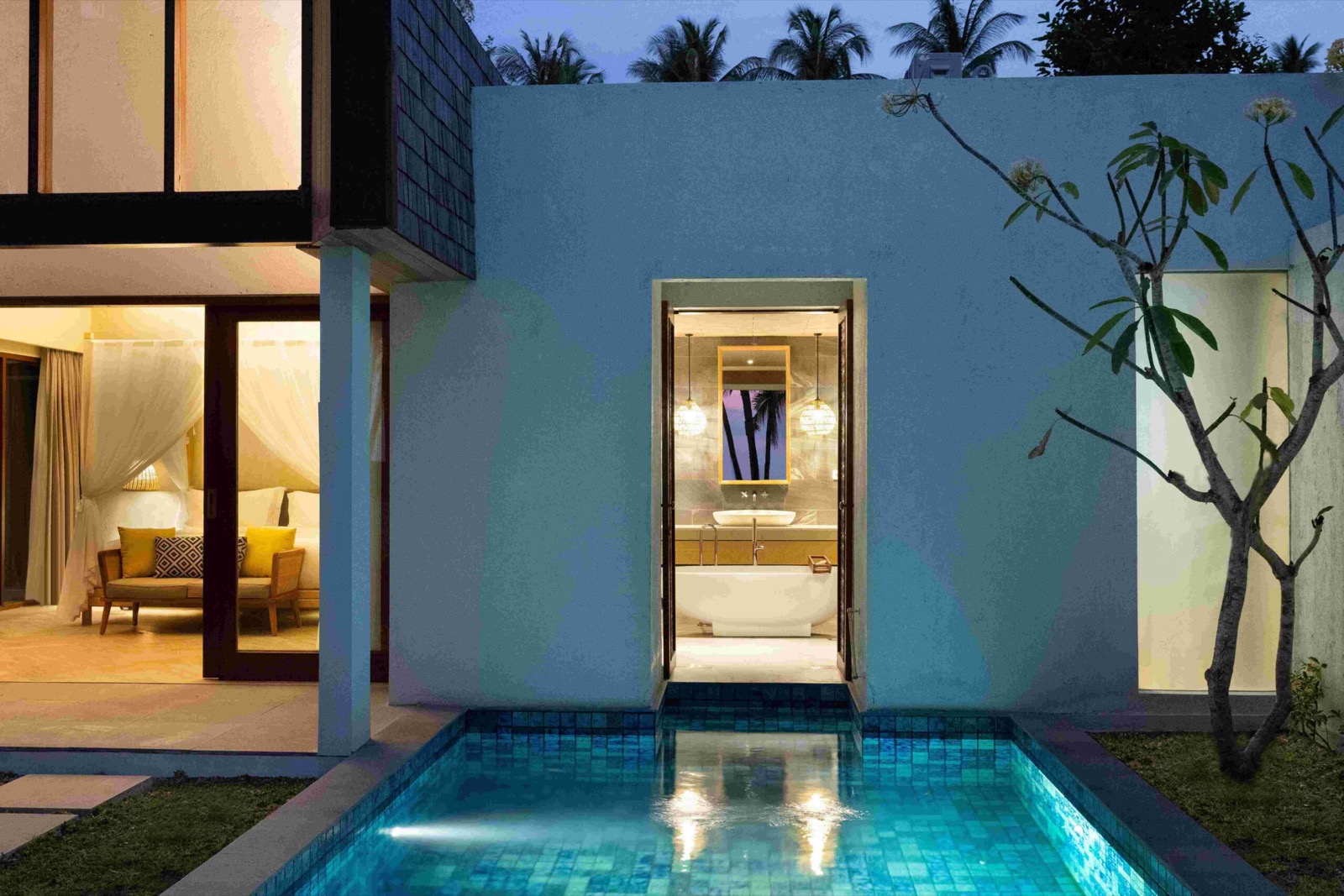 Lit villa courtyard and plunge pool at dusk at The Kayana Beach Lombok, Kecinan