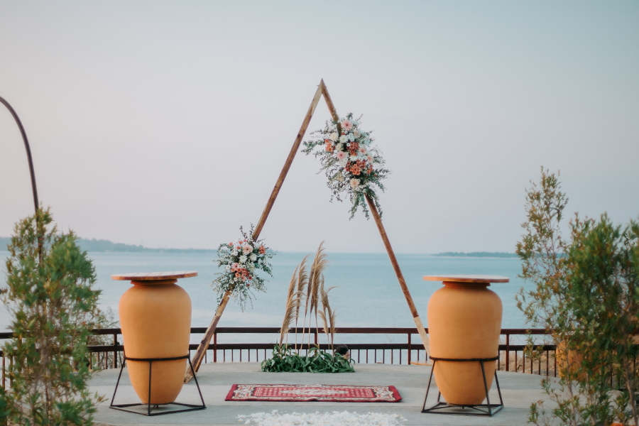 Triangular bamboo arch with pampas grass and terracotta urns set on the clifftop deck above the sea at The Kayana Beach Lombok