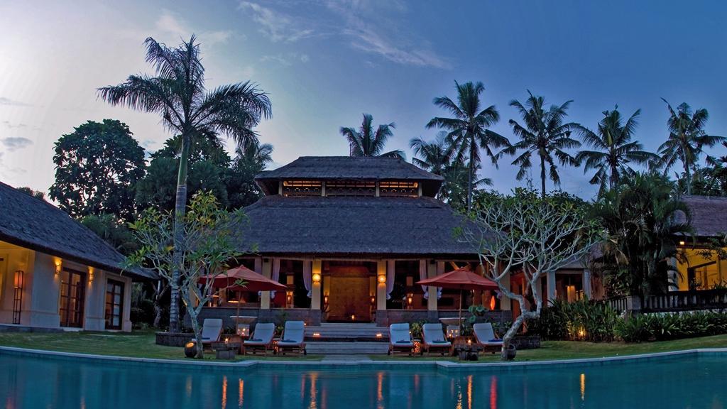 The Lotus Residence main pavilion lit at dusk, seen across the pool