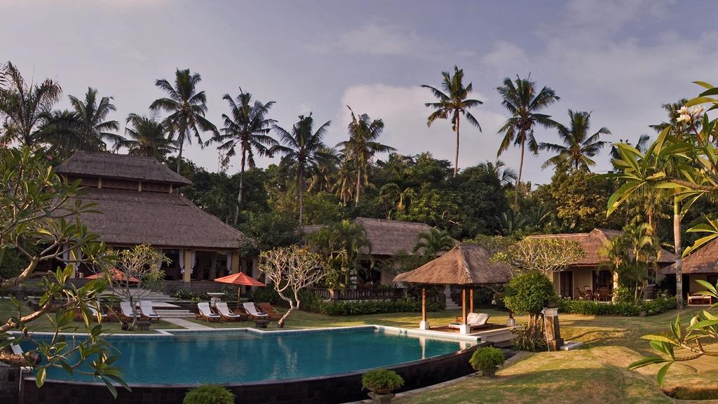 The pool and thatched-roof garden pavilions at The Lotus Residence in daylight