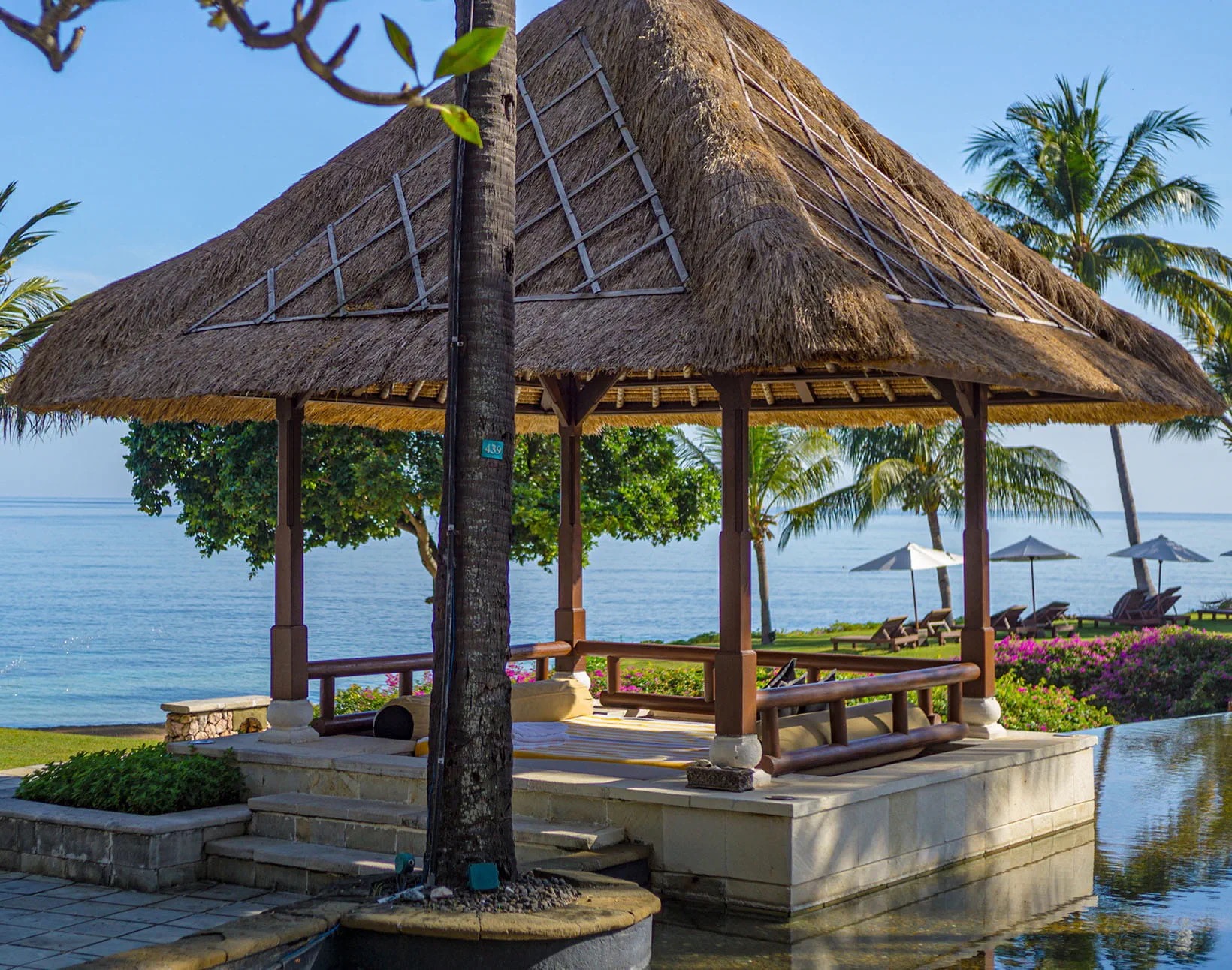 Thatched bale beside the water in the grounds of The Oberoi Beach Resort Lombok, Tanjung