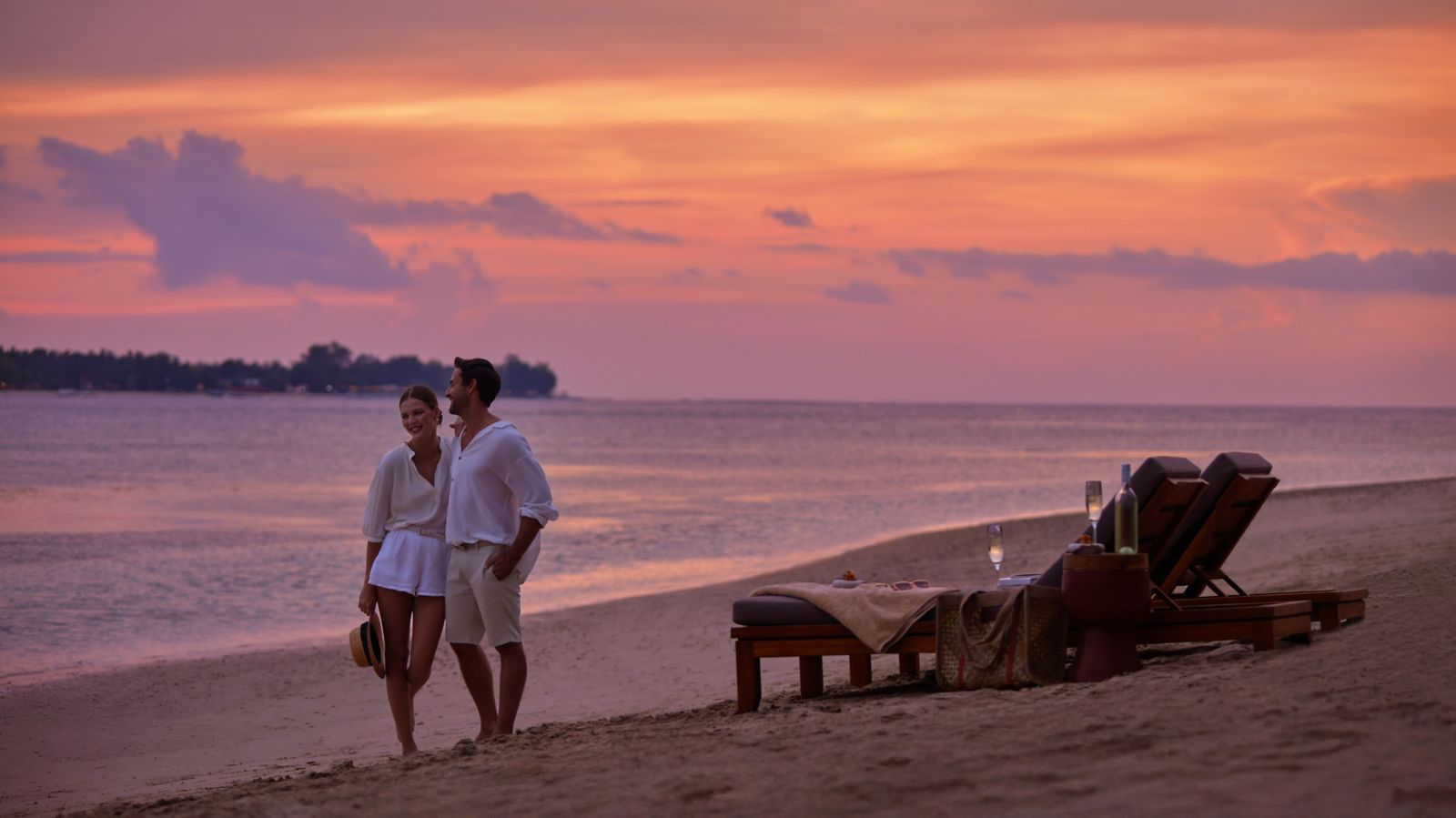 Couple walking the beach at sunset in front of The Sira on Lombok's northwest coast
