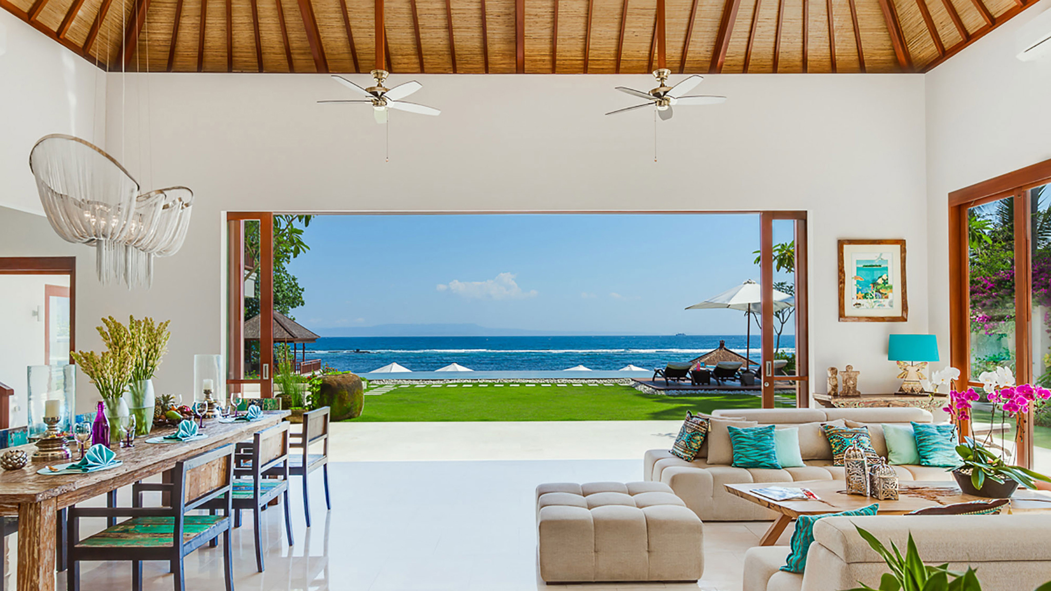 Spacious living and dining area at Tirta Nila Beach House overlooking the ocean through large glass doors
