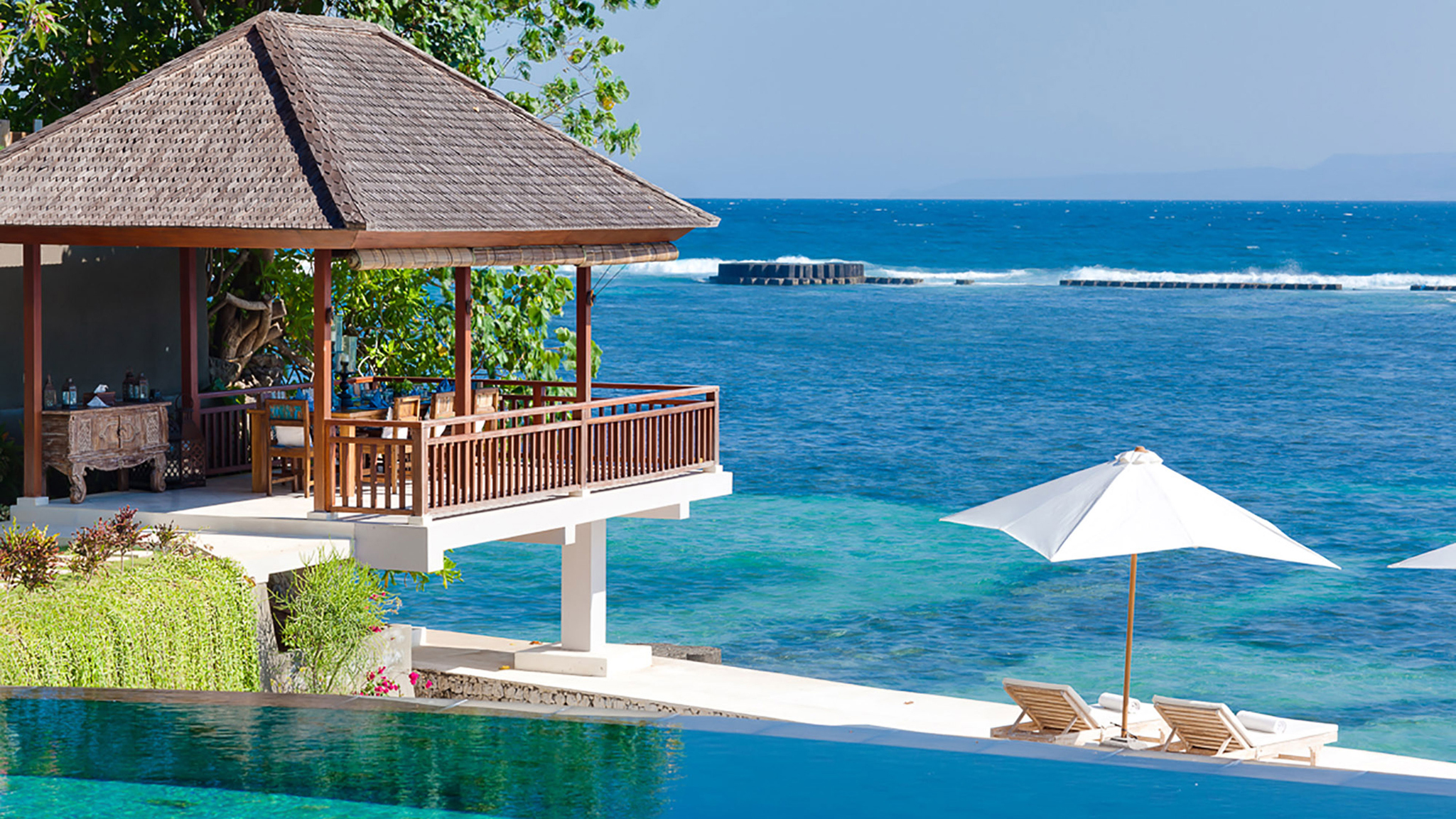 Oceanfront dining pavilion and ocean deck at Tirta Nila with thatched roof and wooden railings