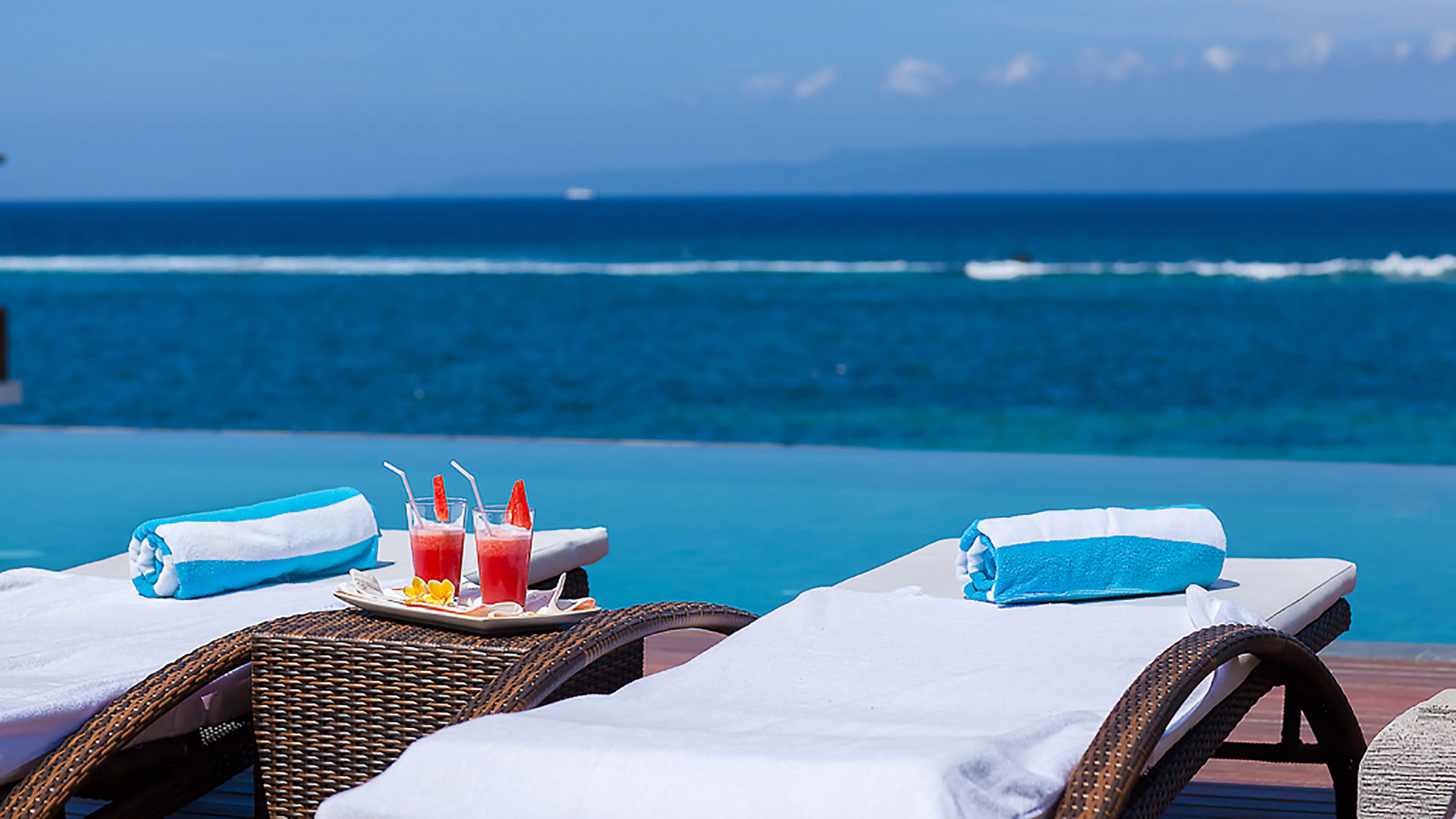 Poolside lounge area at Tirta Nila with refreshments overlooking the ocean, elegant vacation setting