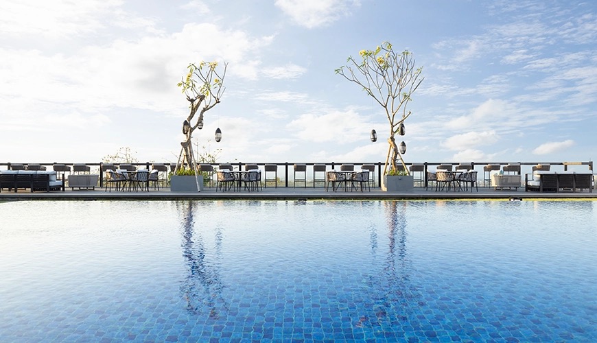 The long infinity pool and lounge terrace at The Tulou Bali above Jimbaran Bay
