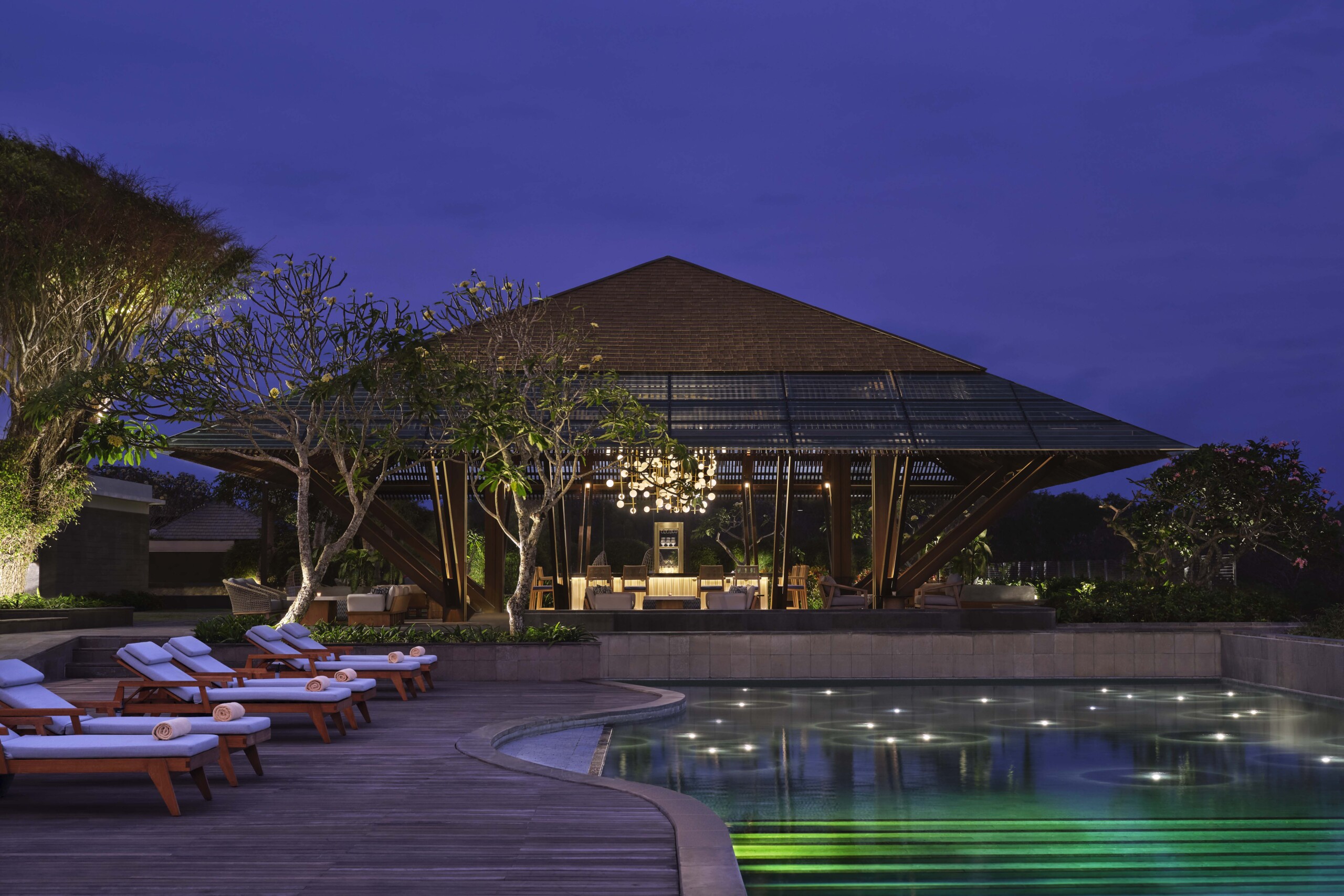Open pavilion and reflecting pool at UMANA Bali lit at dusk