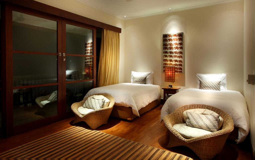 Twin bedroom at Villa Ali Agung with rattan chairs and elephant-motif artwork