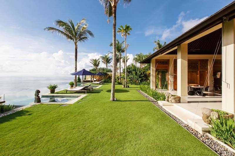 Ocean-view infinity pool and sun loungers on the lawn at Villa Ambar, Uluwatu