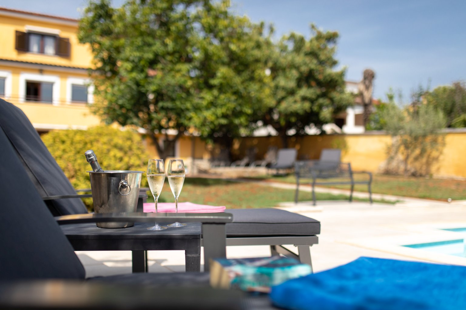 Champagne service on the pool terrace at Villa Ambra, Canggu, with gardens and ocean beyond