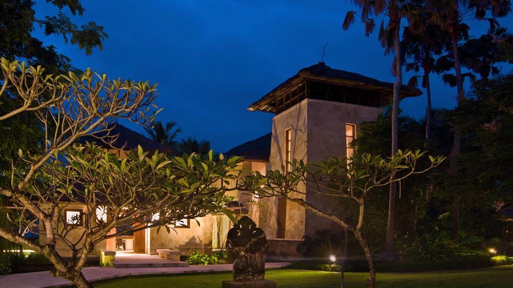 Villa Arika's tower pavilion lit up at night among palm trees