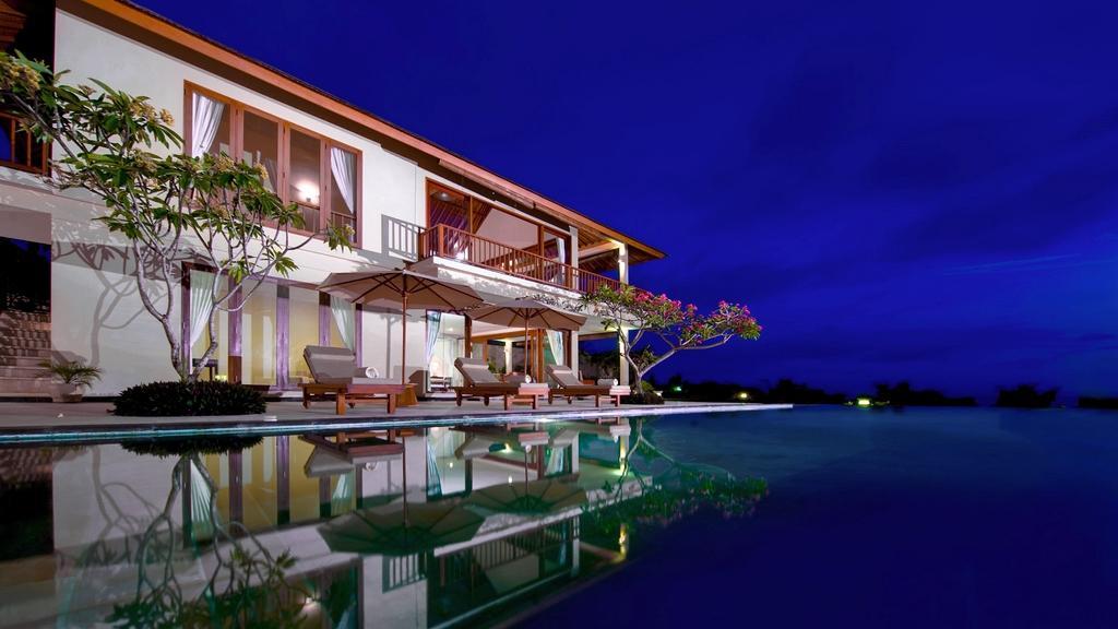 Villa Asada lit up at night, pool and terrace reflecting the villa's lights