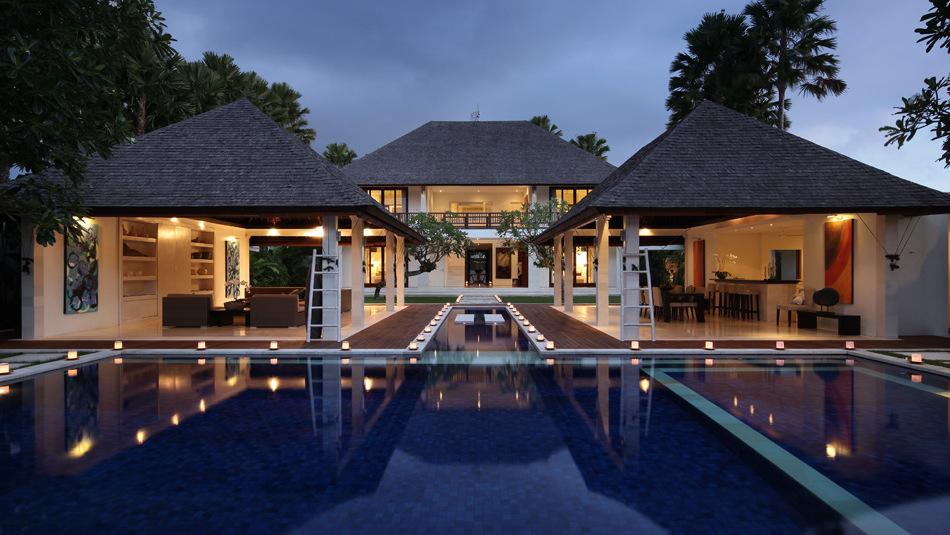Villa Asante at twilight, floating candles lining the reflection pool between the two open-air pavilions