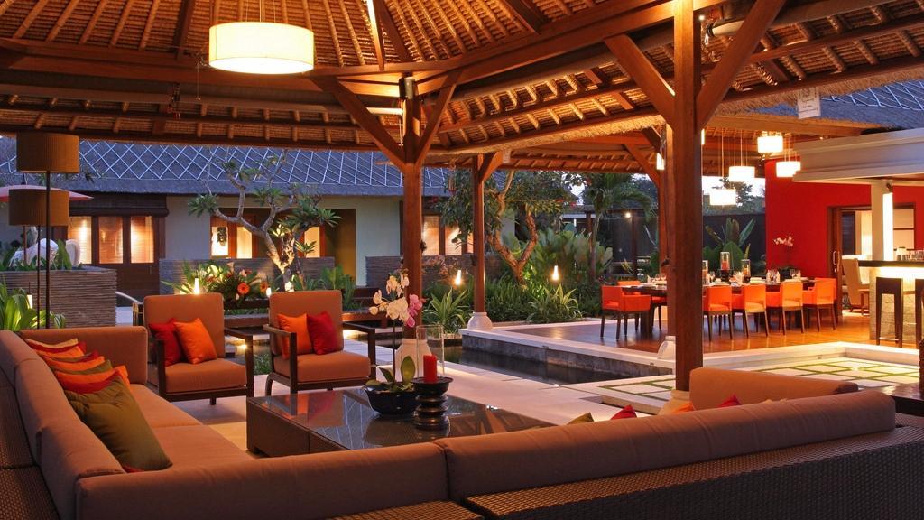 The living pavilion at Villa Asta in the evening, looking out toward the pool and dining area