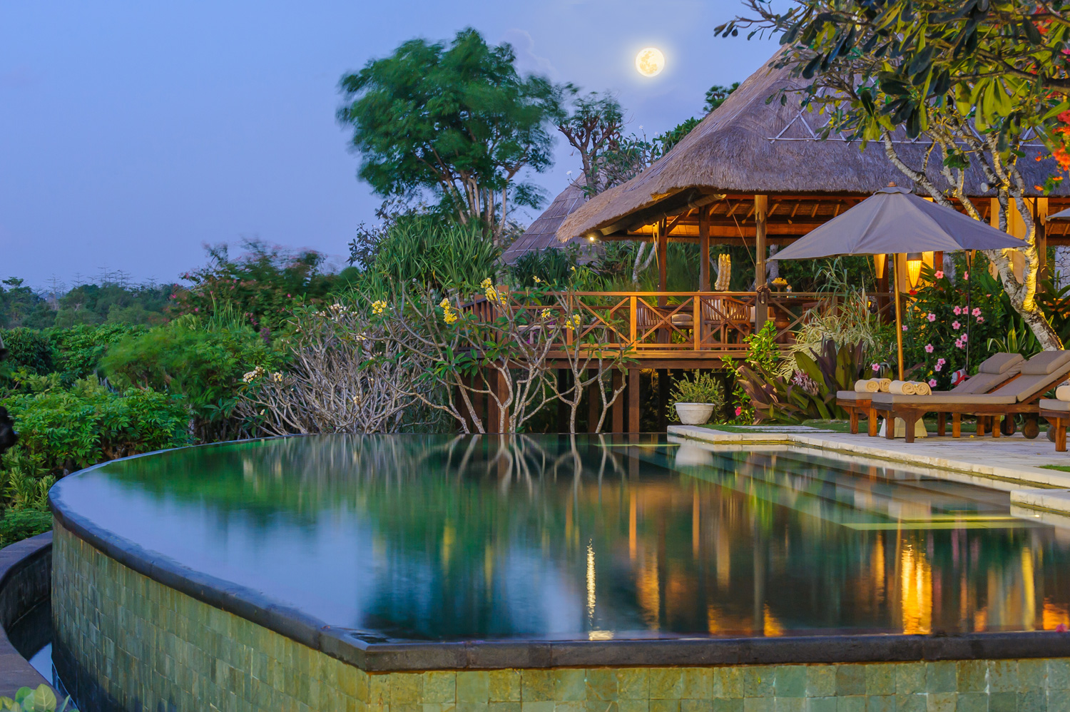 Villa Bayuh Sabbha's poolside balé lit up at night with a full moon overhead