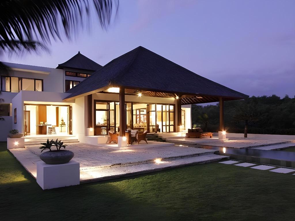 Villa Cahaya's joglo-roofed pavilion and terrace lit up at twilight, on the Ungasan clifftop