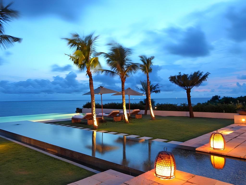Infinity pool and cliffside garden at Villa Cahaya's Sinaran Surga complex in Ungasan, overlooking the Indian Ocean at dusk