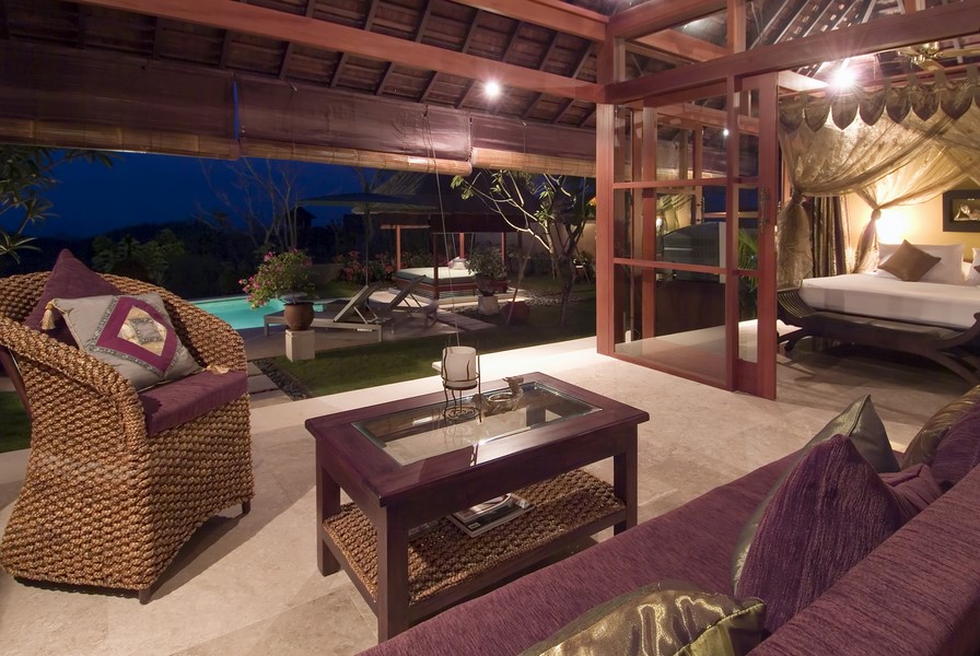 Poolside lounge terrace at Villa Indah Manis at dusk, with garden and gazebo beyond