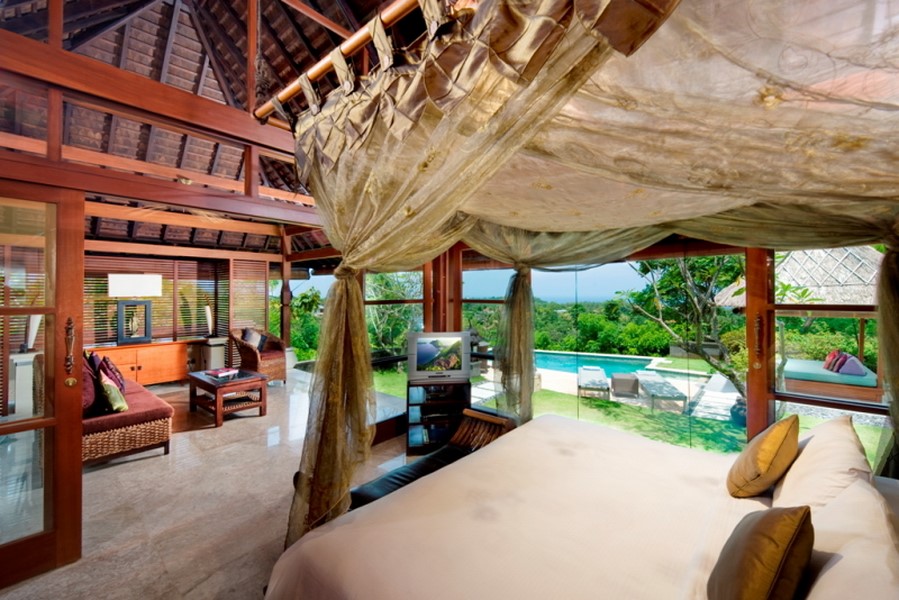 Canopy bed bedroom at Villa Indah Manis with glass doors looking onto the pool and garden