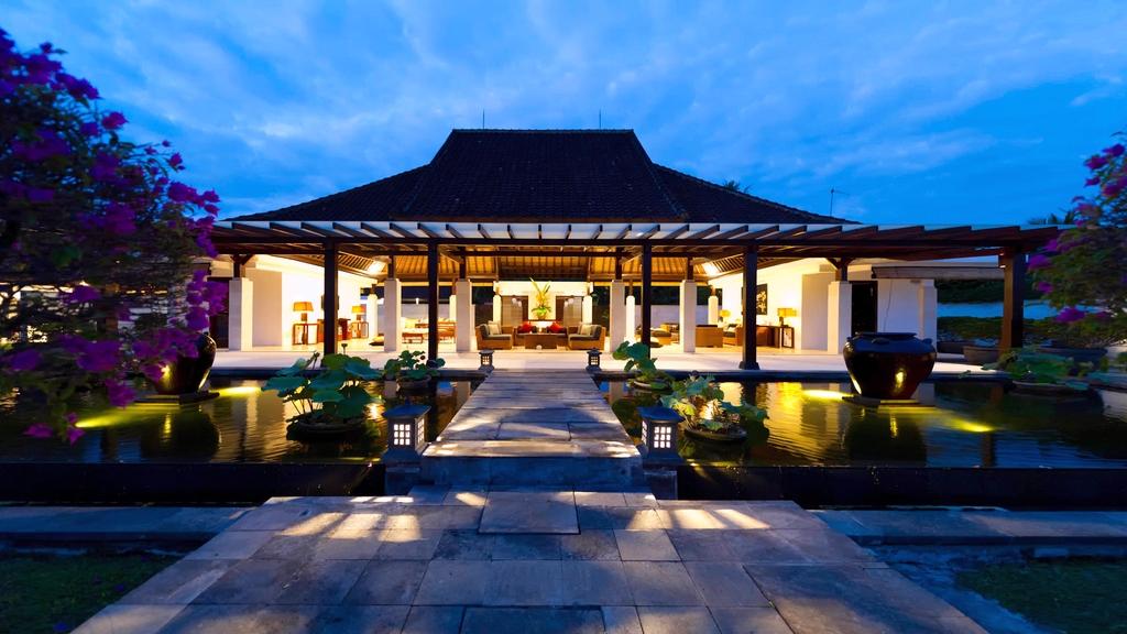 The main pavilion of Villa Kailasha reflected in the entrance lily pond at dusk
