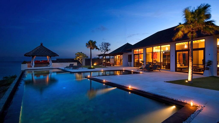 Villa Karang Kembar Tiga at twilight, pool and cliffside gazebo lit above the ocean
