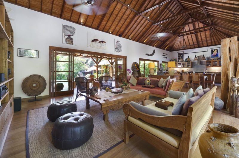 Open-plan living and dining pavilion at Villa Kavaya under a high timber roof, with antique Balinese furniture