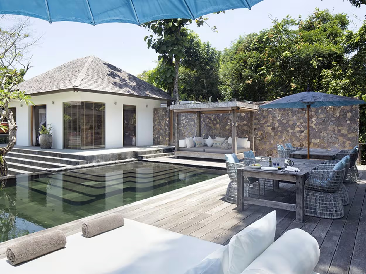 Villa Levi's pool deck in its riverside garden near Echo Beach, Canggu, built from reclaimed wood and natural stone