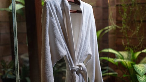 Garden bathroom with a robe and tropical planting at Villa Majapahit Nataraja