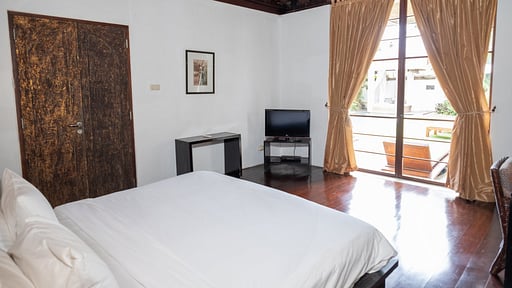 Bedroom with polished hardwood floors and a private balcony at Villa Majapahit Nataraja