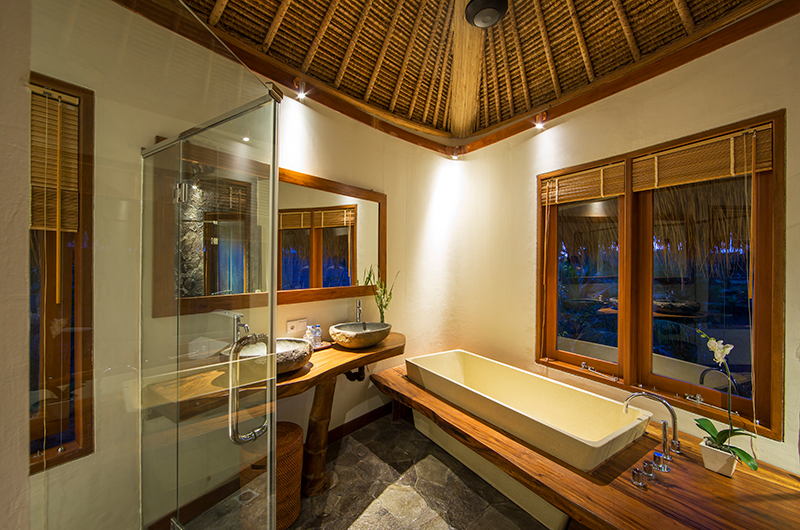 Ensuite bathroom at Villa Omah Padi with a stone tub and double vanity under a bamboo roof