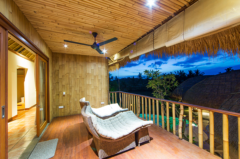 Balcony daybed at Villa Omah Padi under a bamboo ceiling, looking out over the rice fields at dusk
