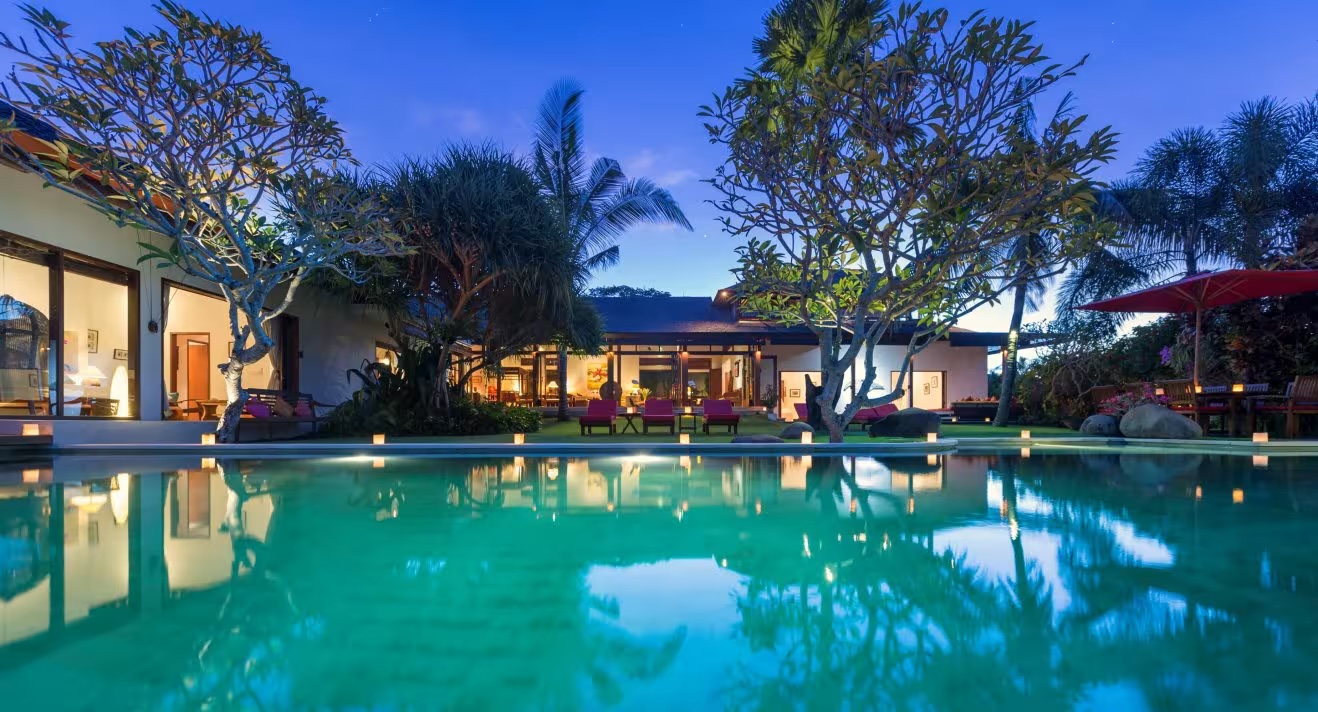 Villa Paloma lit at night, the pool and garden glowing between the two villa buildings